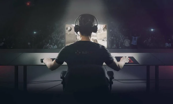 киберспортсмен за компьютером на сцене под софитами